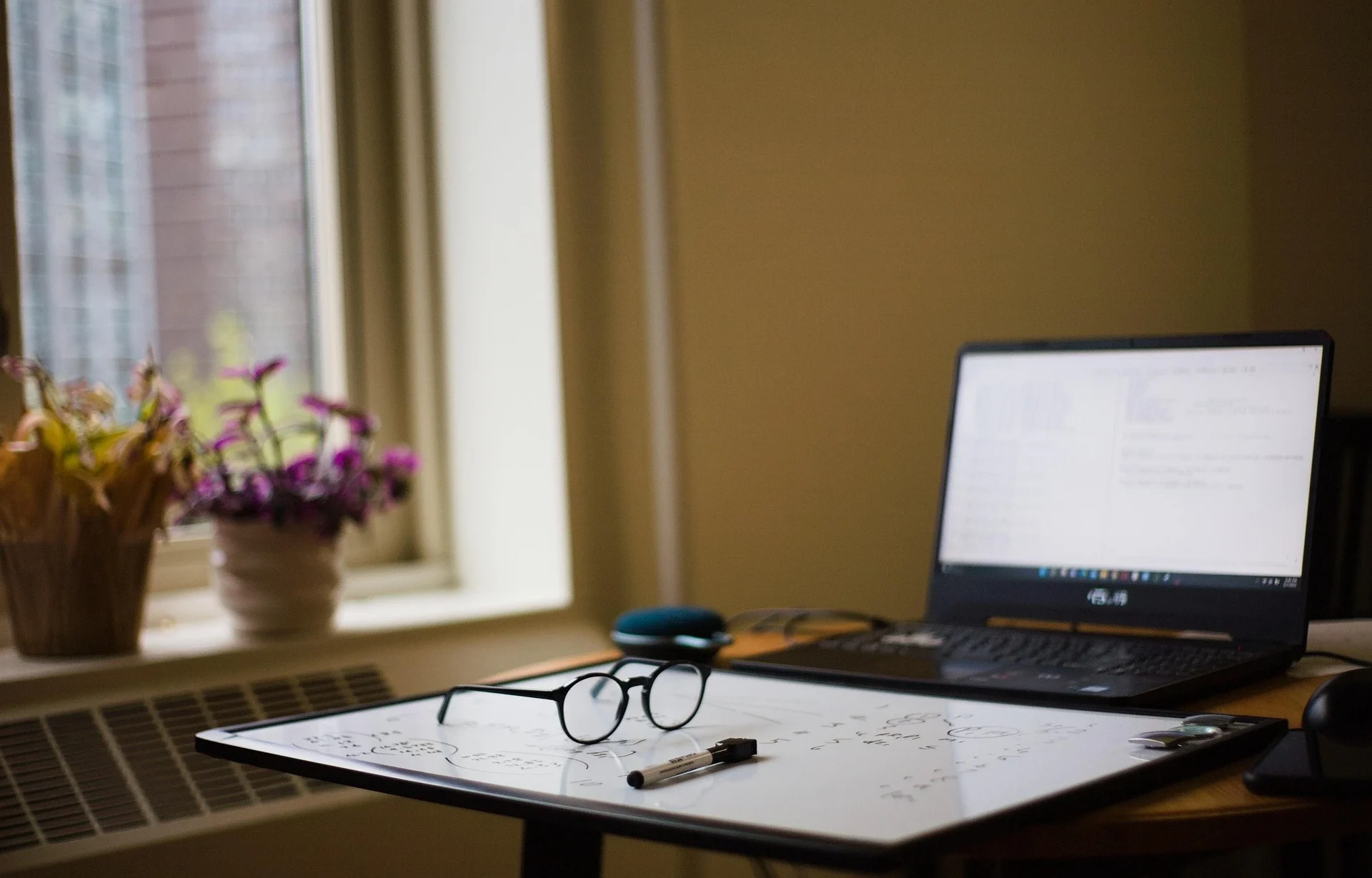 Schreibtisch mit Laptop, Notizen und Brille als Symbol für die Prüfung einer WEG-Jahresabrechnung.